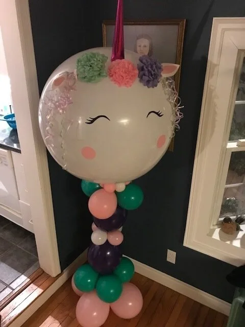 Whimsical unicorn balloon sculpture with a hand-crafted face